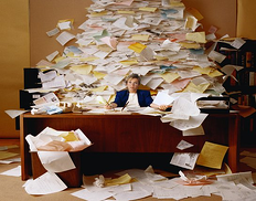 Woman buried in paper documents at her desk.
